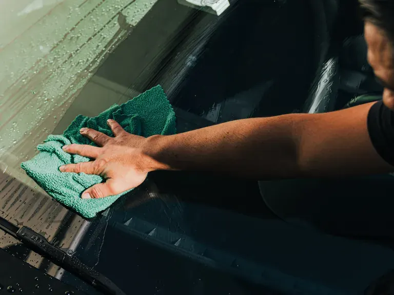 Auto Detailing Ecophant Auto technician hand-drying a windshield during auto detailing